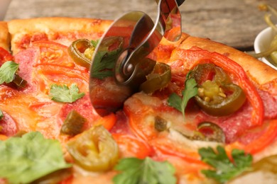 Cutting delicious pizza Diablo at table, closeup