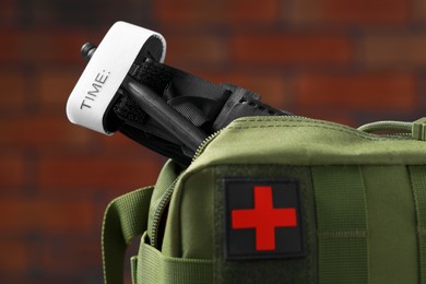 Photo of Military first aid kit and tourniquet on blurred background, closeup