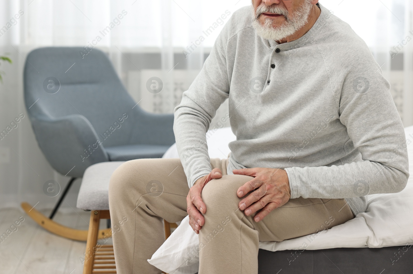 Photo of Arthritis symptoms. Man suffering from pain in knee at home