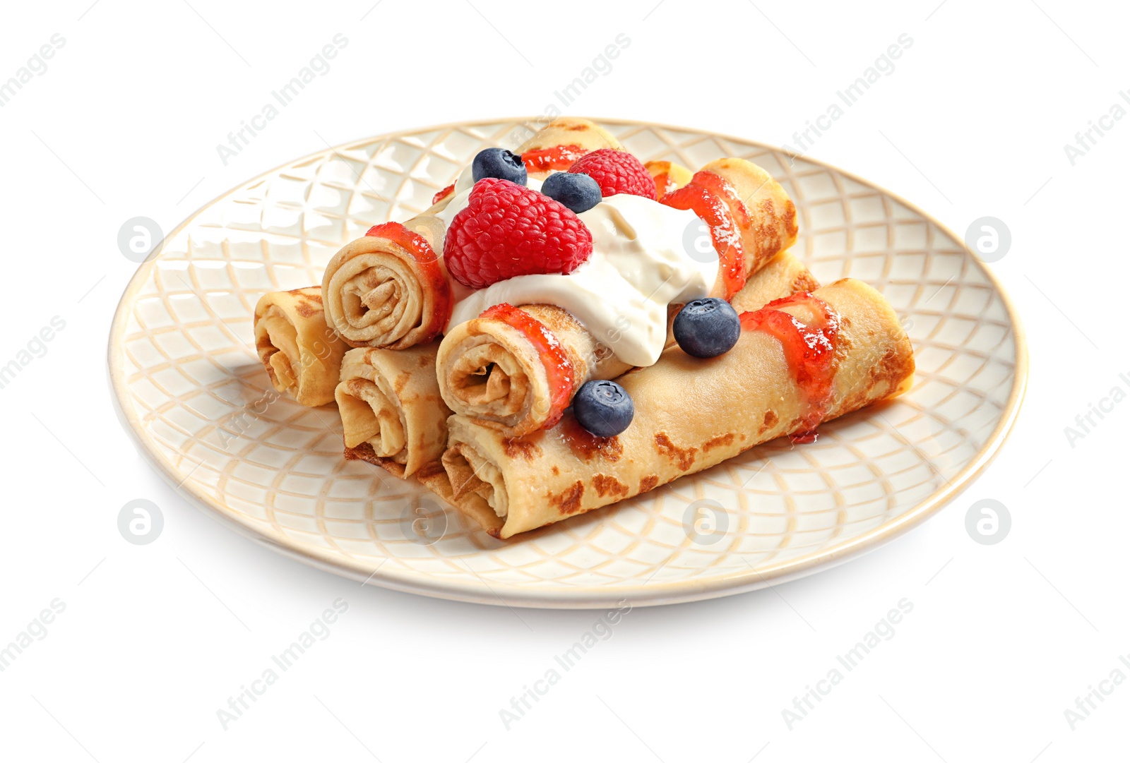 Photo of Thin pancakes with syrup, cream and berries on plate against white background