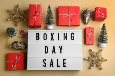 Lightbox with phrase BOXING DAY SALE and Christmas decorations on beige background, flat lay