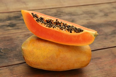 Photo of Tasty whole and half papaya fruits on wooden table, closeup