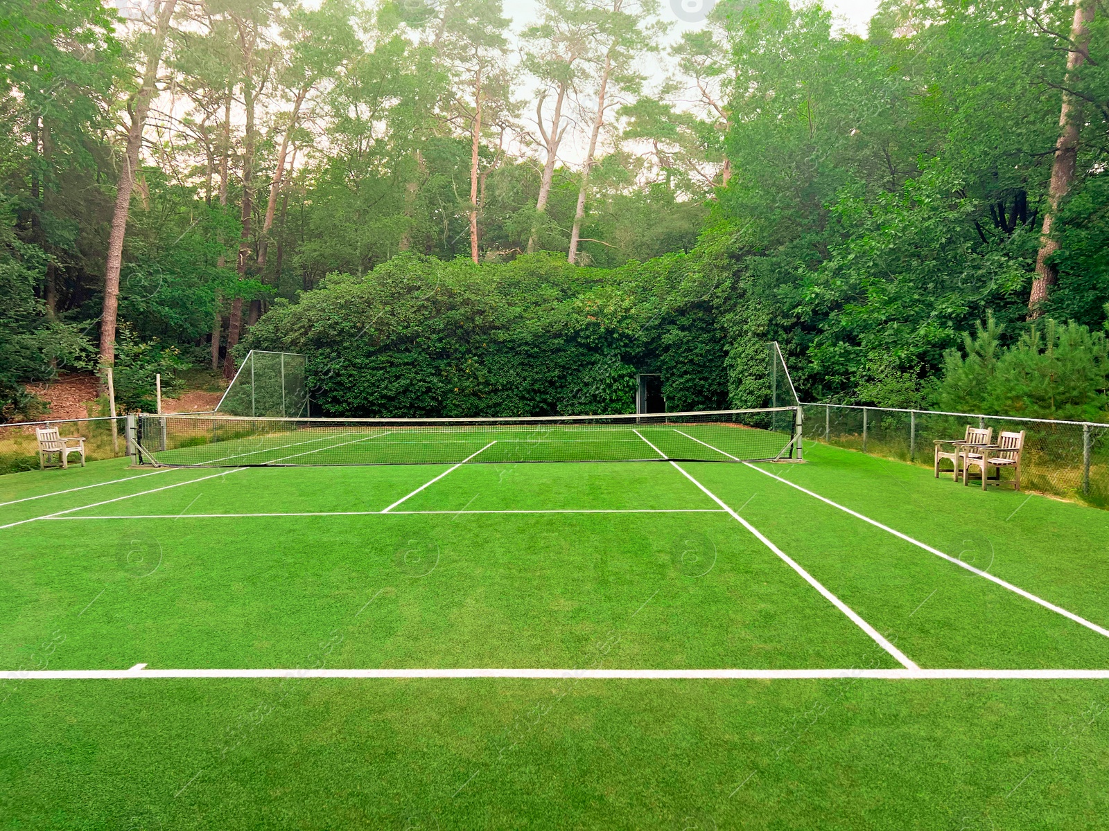 Photo of Tennis court with green grass and net outdoors