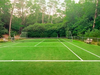 Photo of Tennis court with green grass and net outdoors