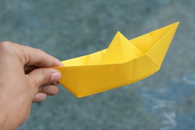 Photo of Woman holding yellow paper boat outdoors, closeup