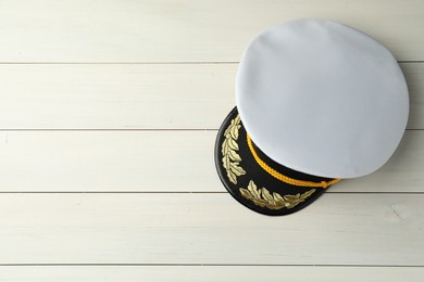 Photo of Peaked cap with accessories on white wooden background, top view. Space for text