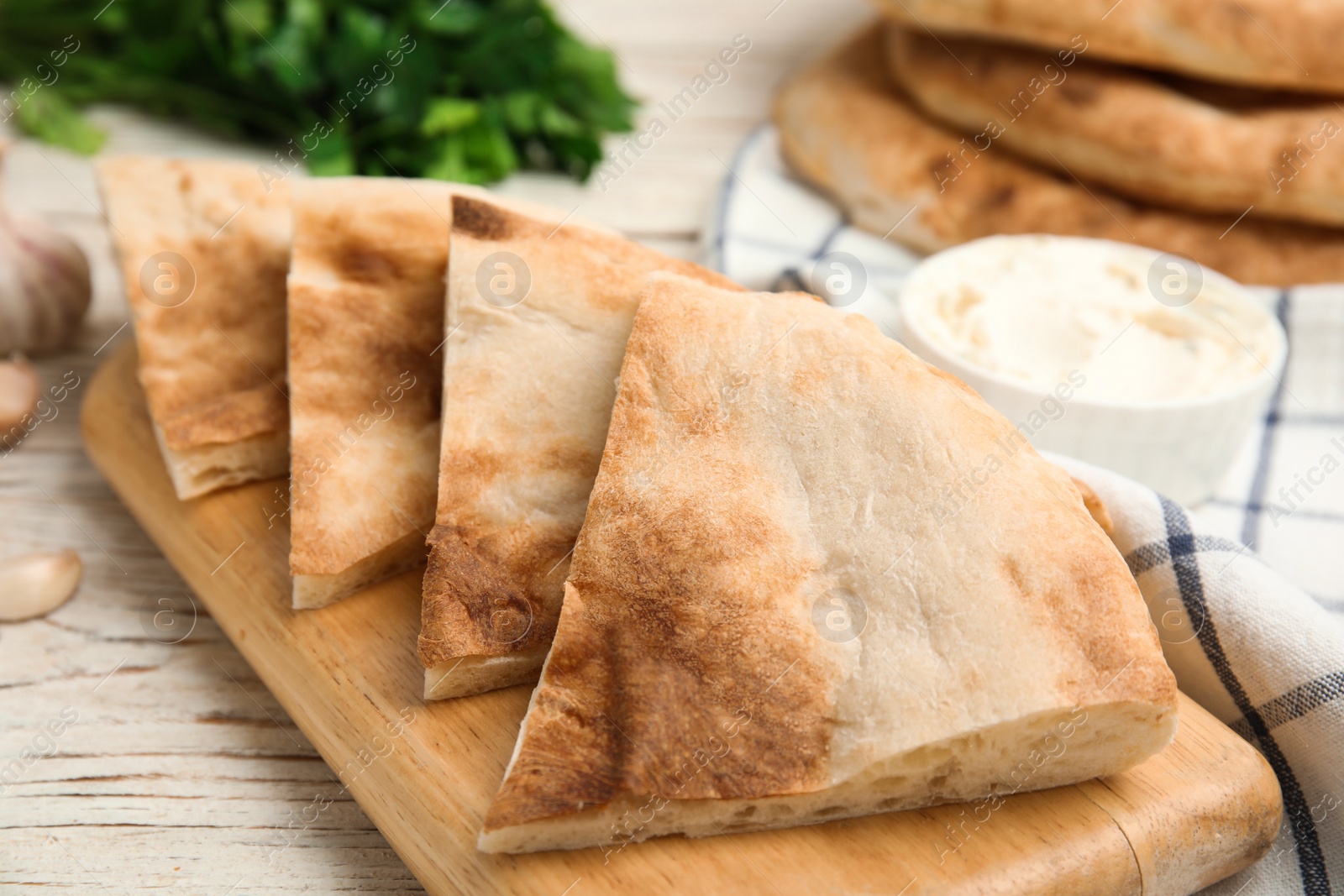 Photo of Cut pita bread on white wooden table, closeup