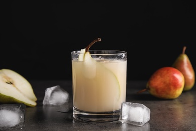 Photo of Glass of fresh pear juice, fruits and ice cubes on grey table