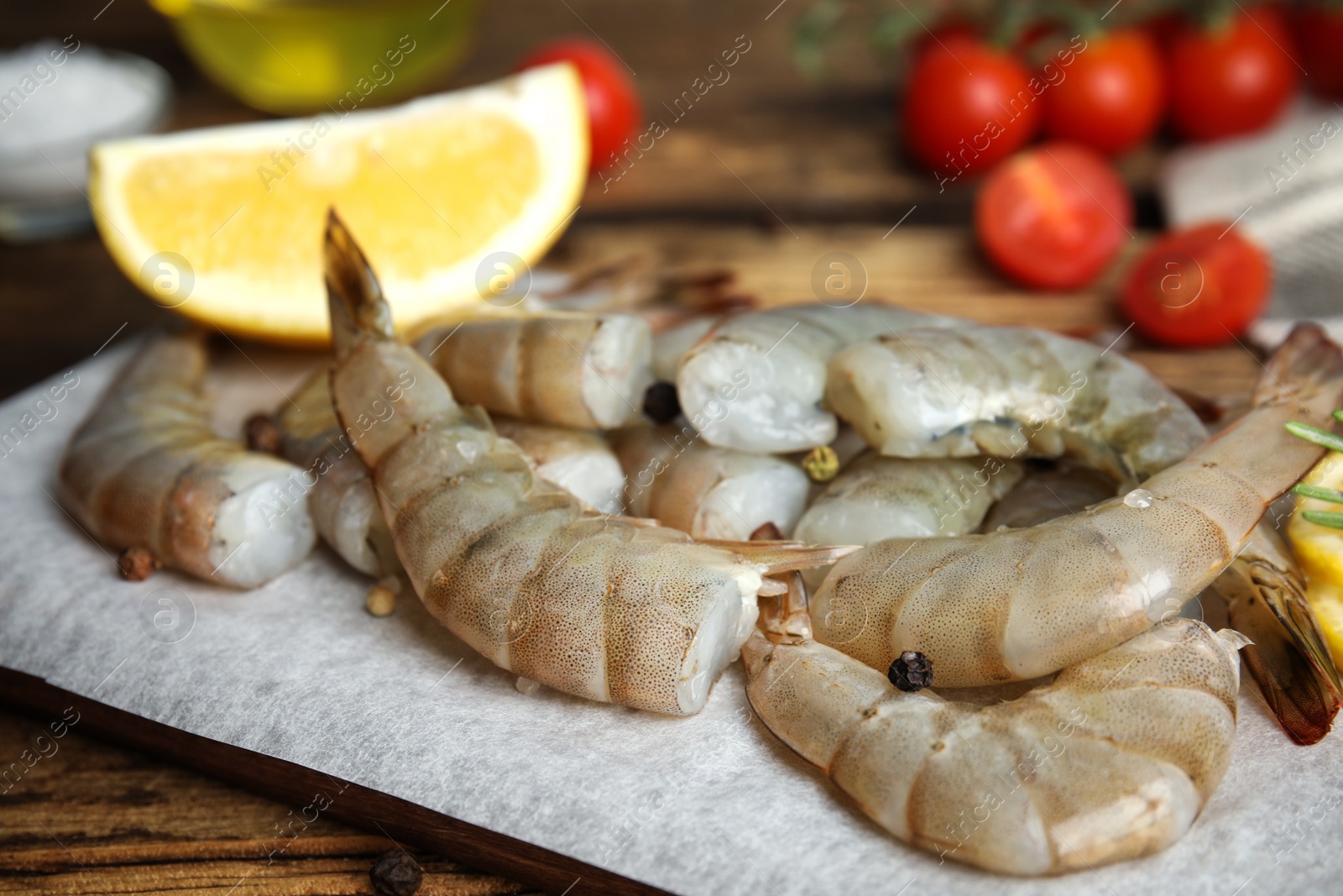 Photo of Fresh raw shrimps with lemon on wooden board, closeup