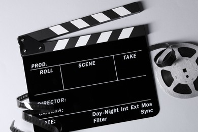 Photo of Clapperboard and film reel on grey background, flat lay