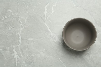 Photo of Stylish empty ceramic bowl on grey table, top view and space for text. Cooking utensil