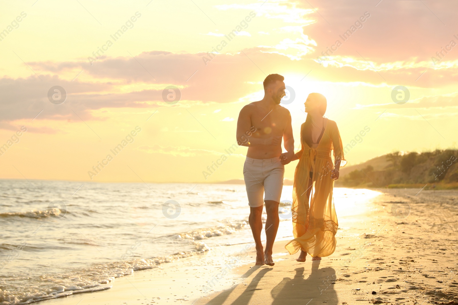 Photo of Happy young couple running together on beach at sunset