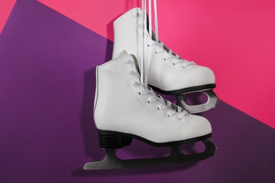 Photo of Pair of white ice skates hanging on color background