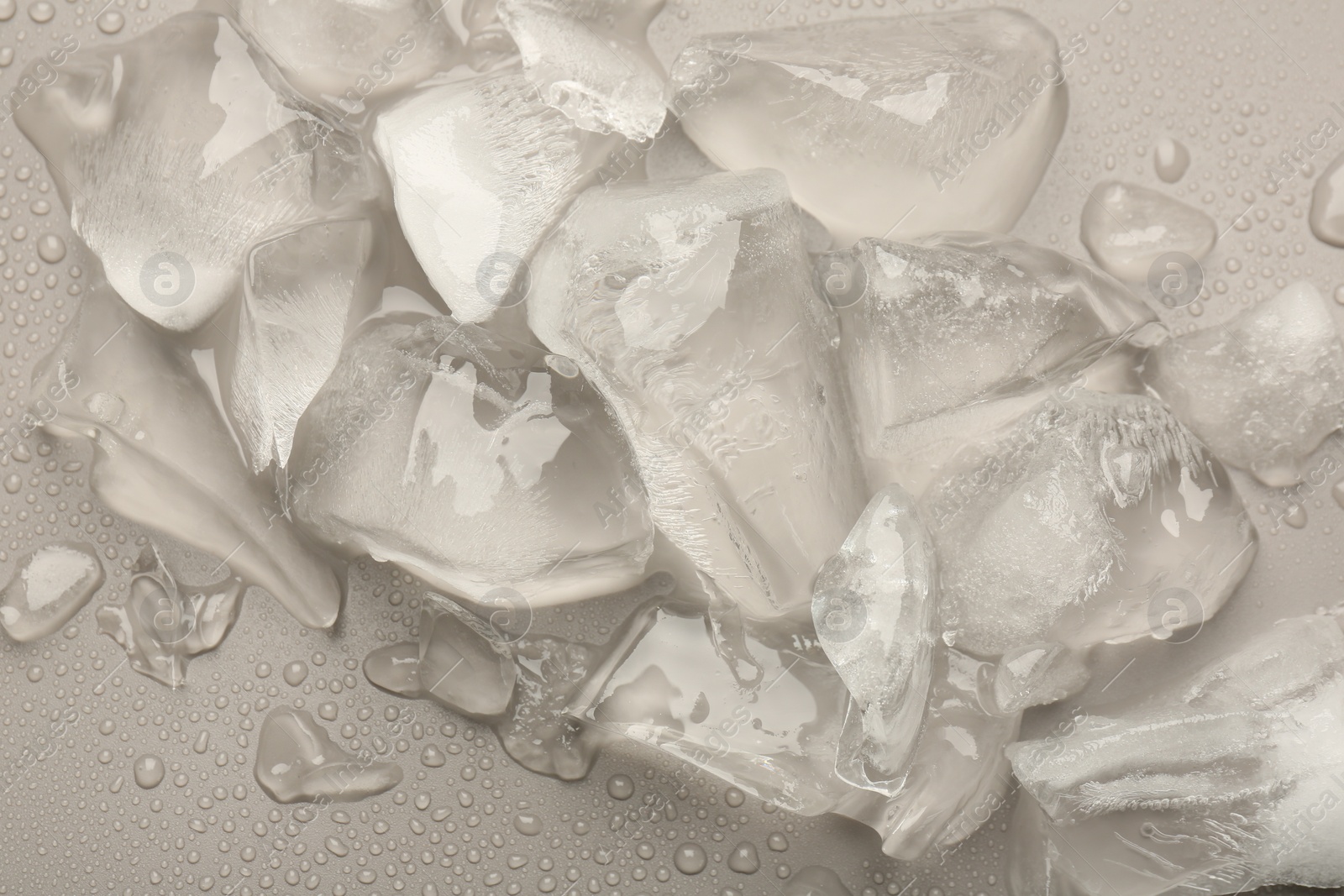 Photo of Pieces of crushed ice on grey background, top view