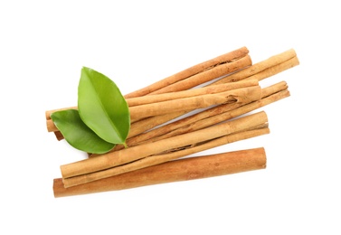 Aromatic dry cinnamon sticks and green leaves on white background, top view