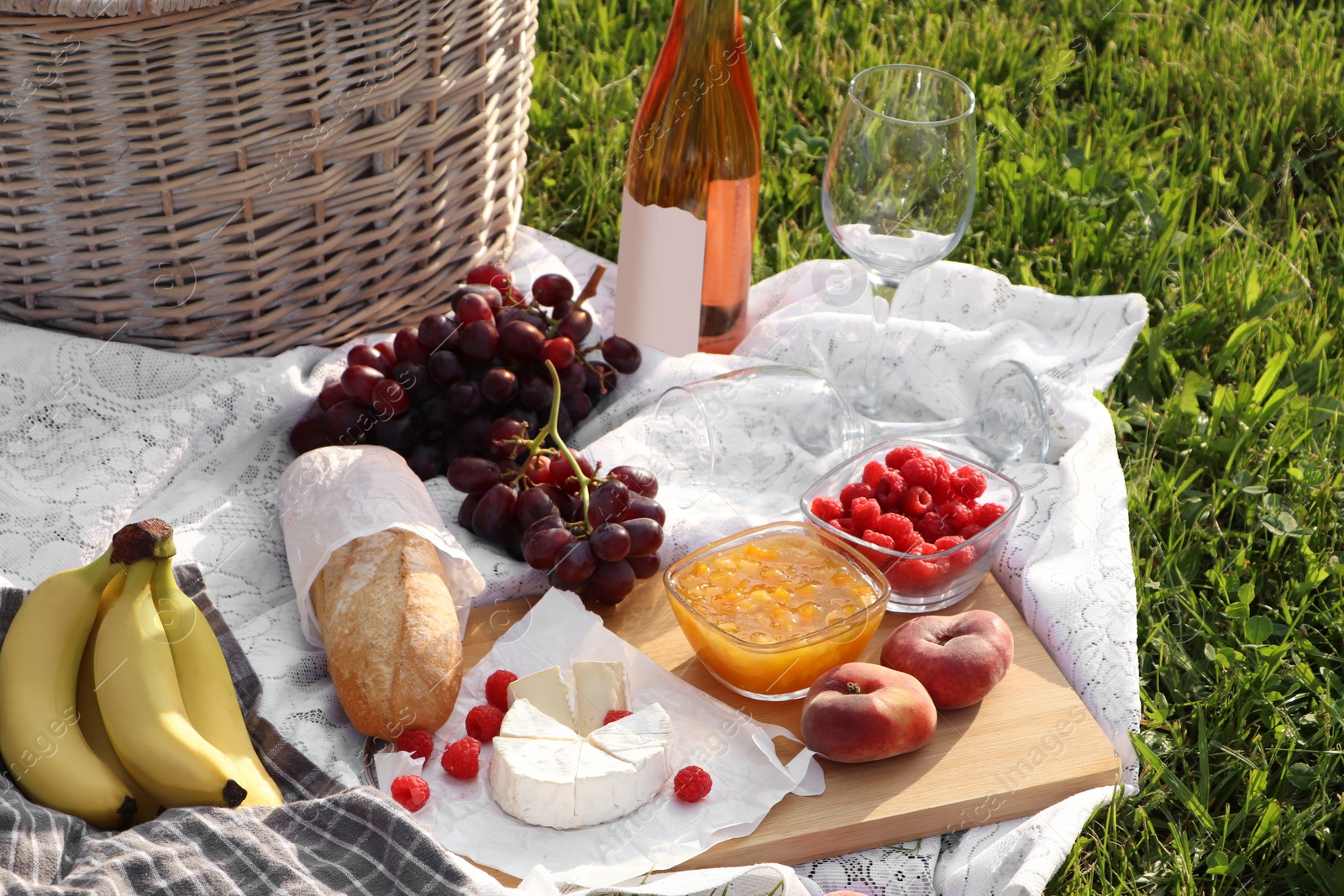 Photo of Picnic blanket with tasty food and cider on green grass outdoors