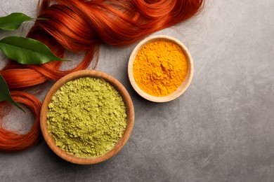 Henna, turmeric powder, red strand and green leaves on grey table, flat lay with space for text. Natural hair coloring