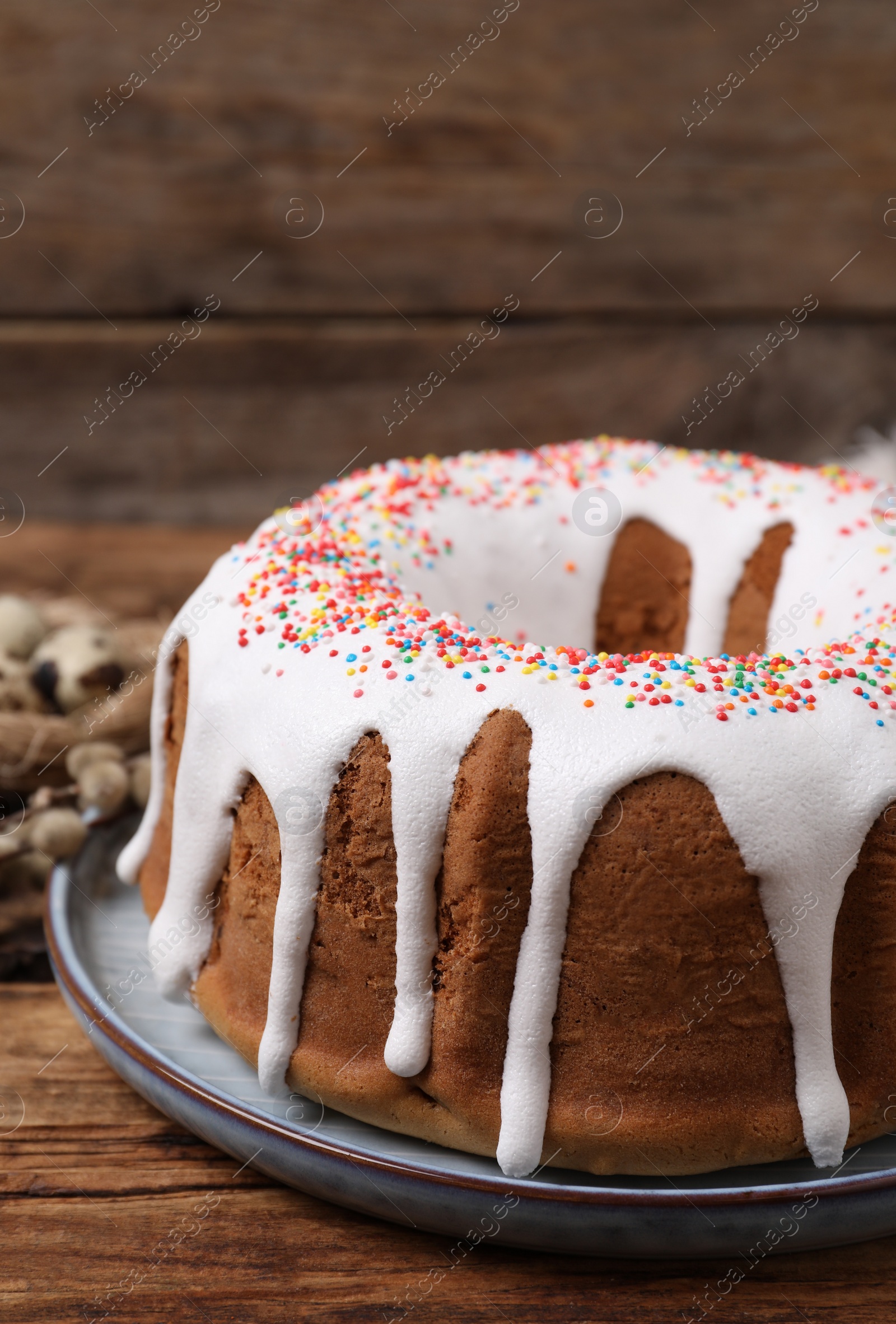 Photo of Glazed Easter cake with sprinkles on wooden table, closeup