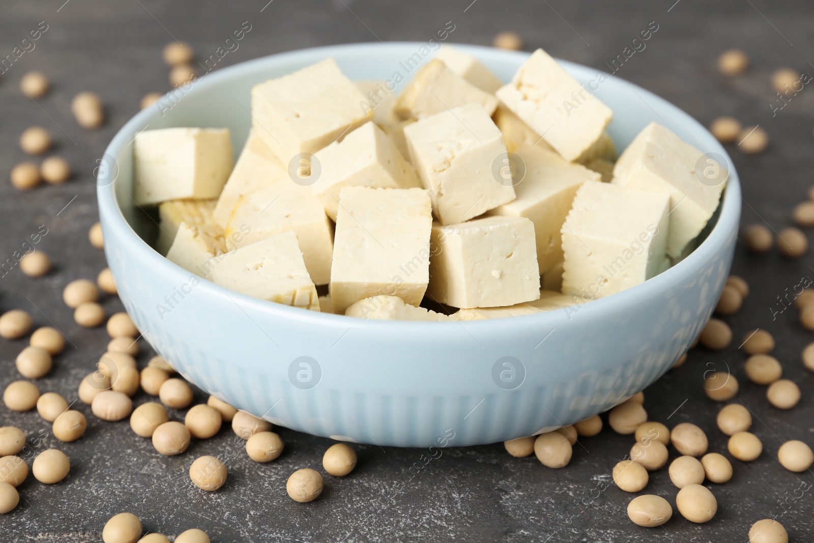 Photo of Cut tofu and soya beans on grey table, closeup