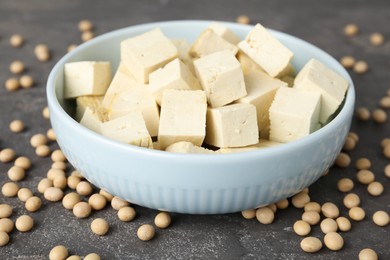Photo of Cut tofu and soya beans on grey table, closeup