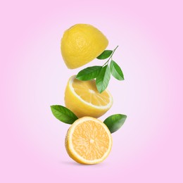 Image of Cut fresh lemons with green leaves falling on pink background