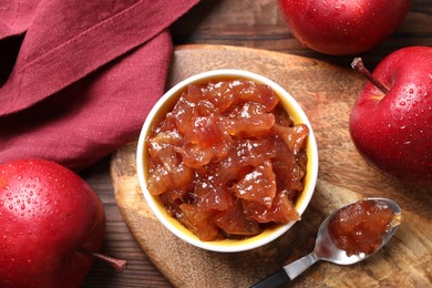 Photo of Bowl of delicious apple jam and fresh fruits on wooden table, flat lay