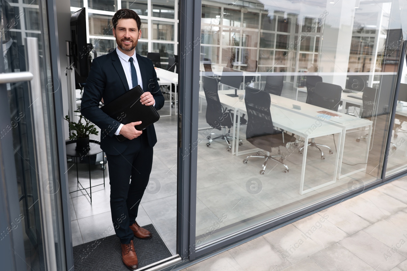 Photo of Happy real estate agent with leather portfolio in office