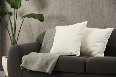 Photo of Soft white pillows and blanket on sofa indoors