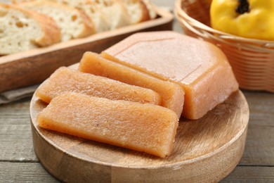 Tasty sweet quince paste, fresh fruit and bread on wooden table, closeup