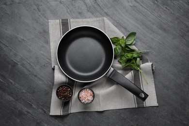 Frying pan, basil and spices on grey table, top view