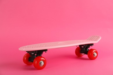 Photo of Bright skateboard on pink background. Space for text