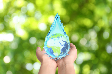 Image of Woman holding icon of Earth in water drop on blurred green background, closeup. Ecology concept