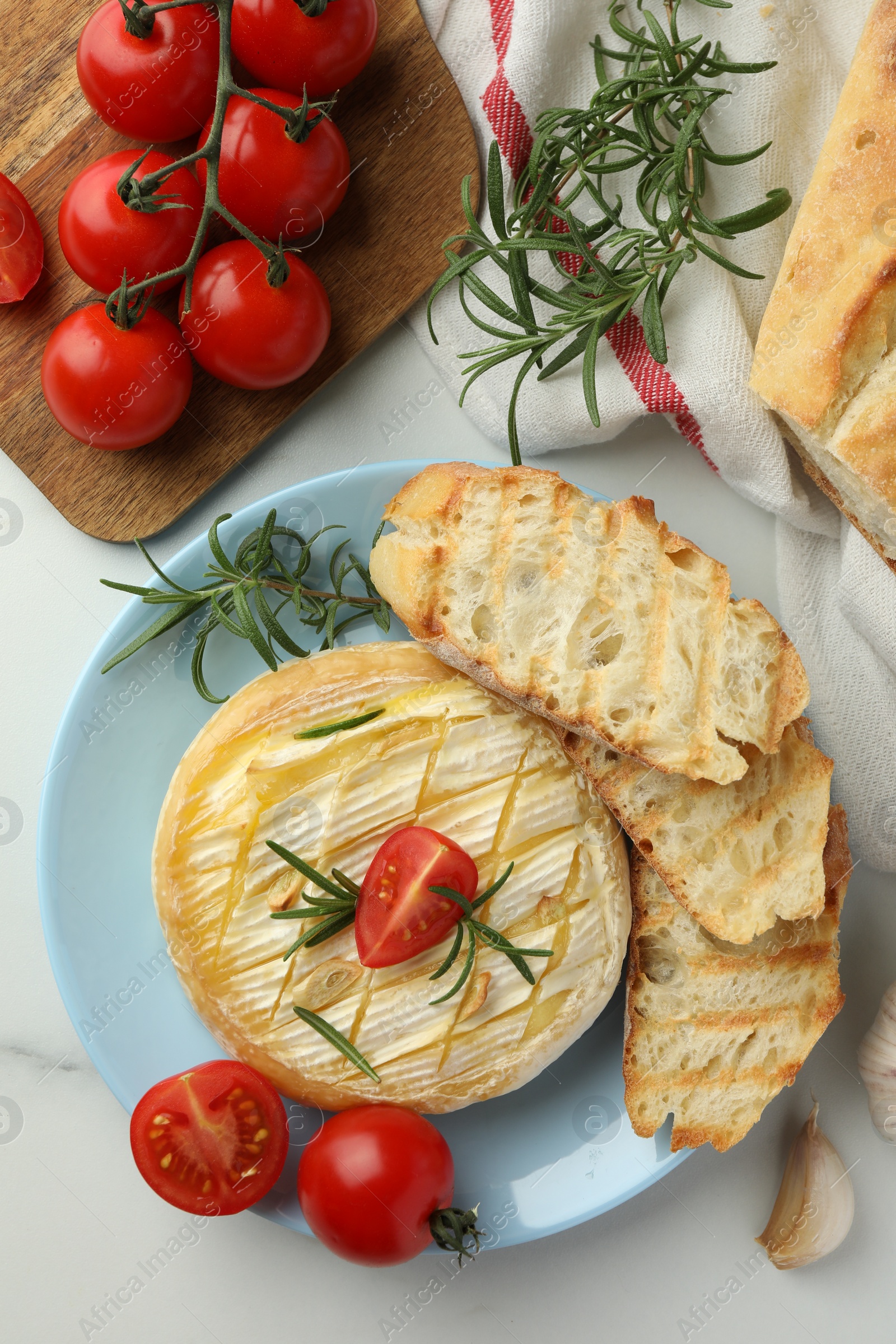 Photo of Tasty baked brie cheese served on white table, flat lay