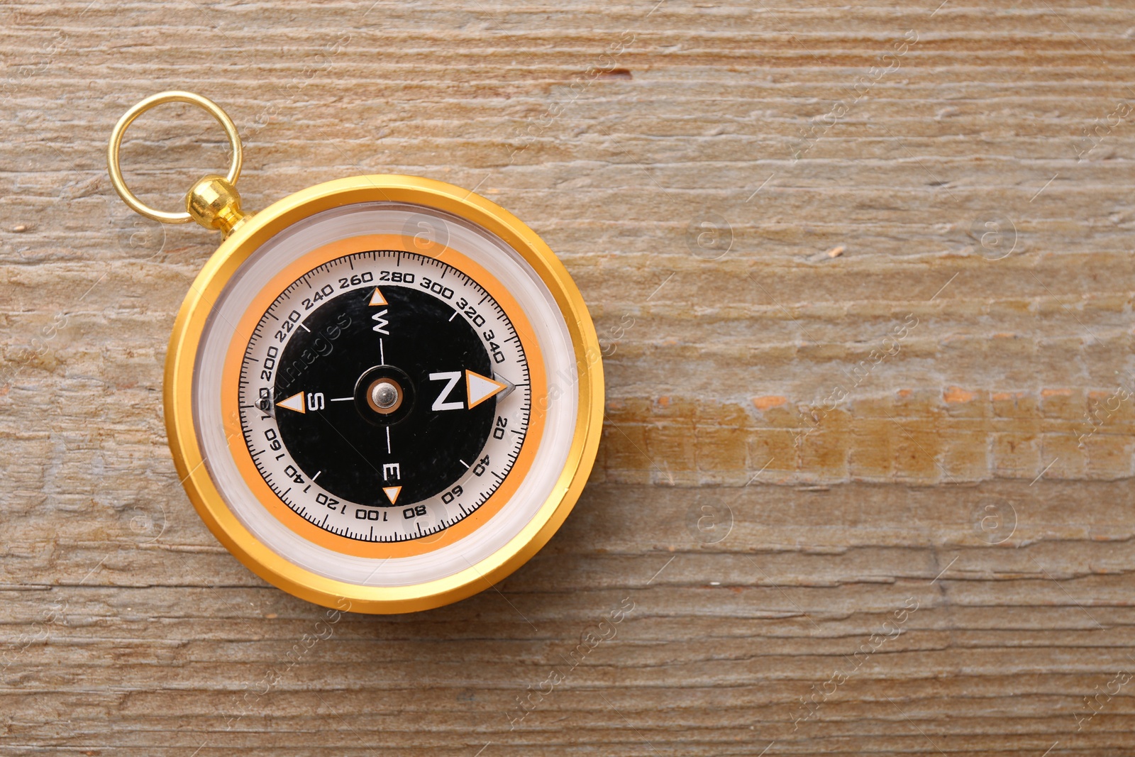 Photo of One compass on wooden table, top view. Space for text