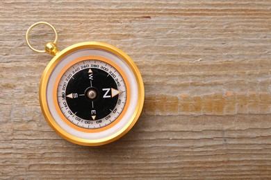 Photo of One compass on wooden table, top view. Space for text