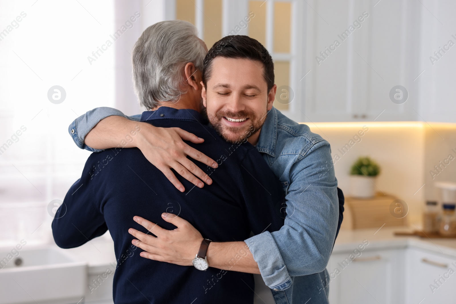 Photo of Happy son and his dad hugging at home