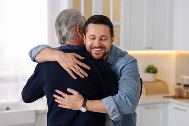 Photo of Happy son and his dad hugging at home