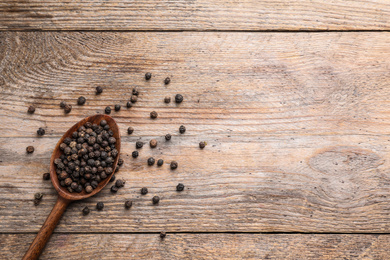 Photo of Peppercorns on wooden table, flat lay. Space for text