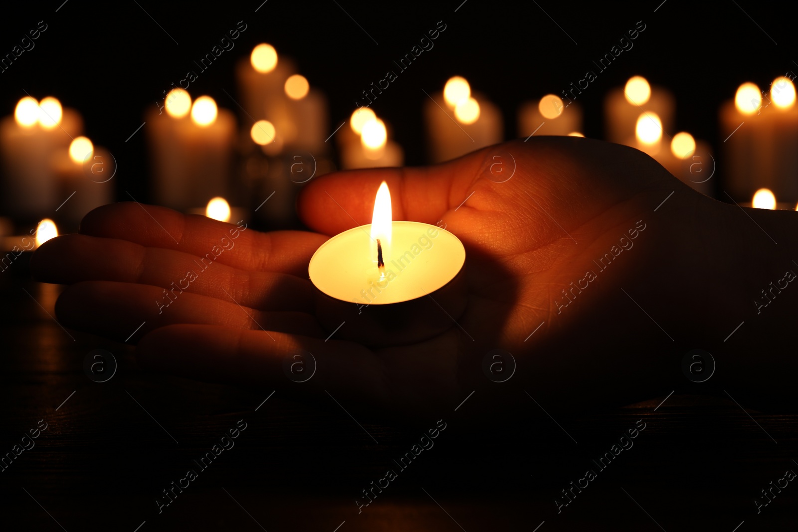 Photo of Woman with burning candle in darkness, closeup. Memory day