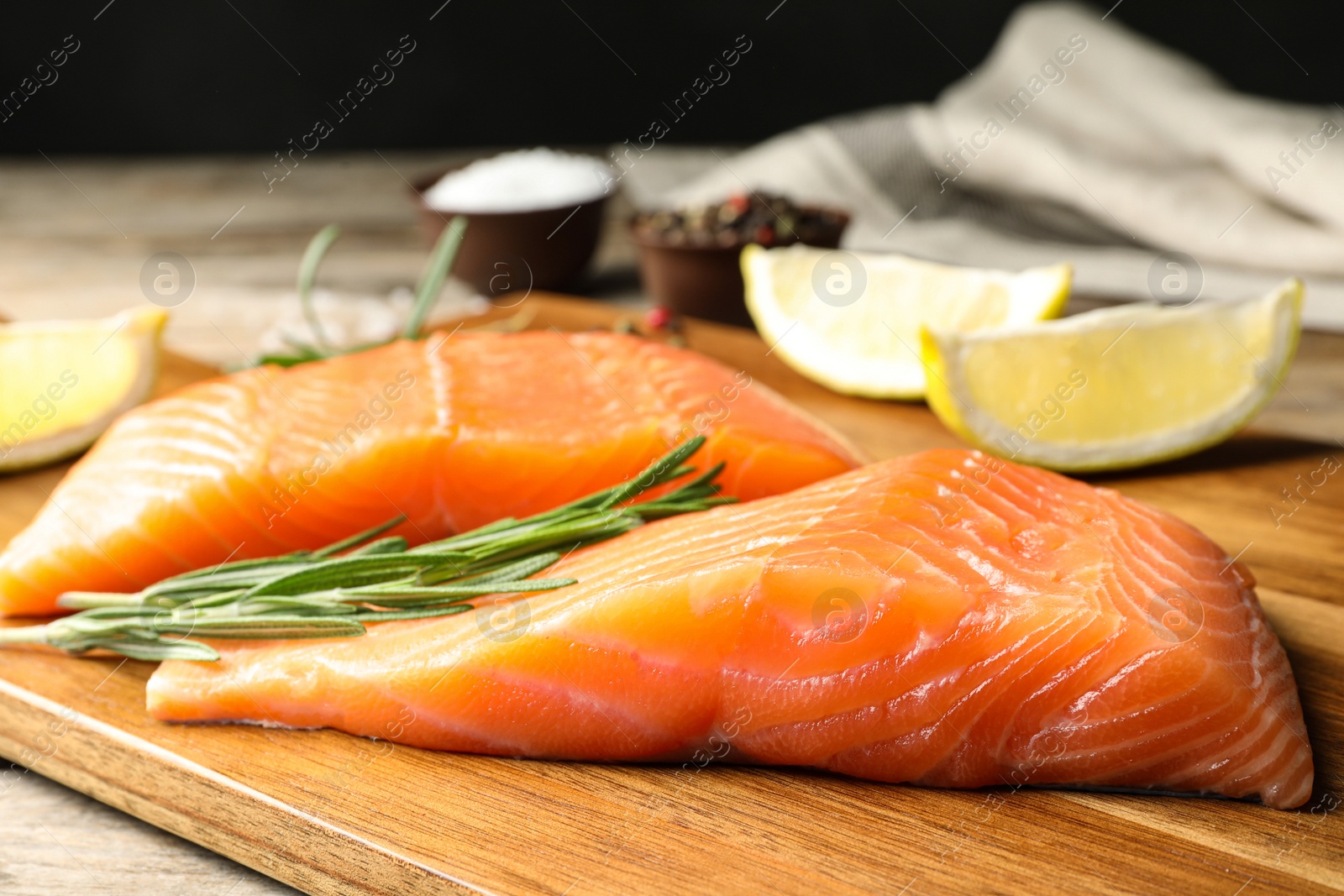Photo of Wooden board with salmon fillet on table, closeup