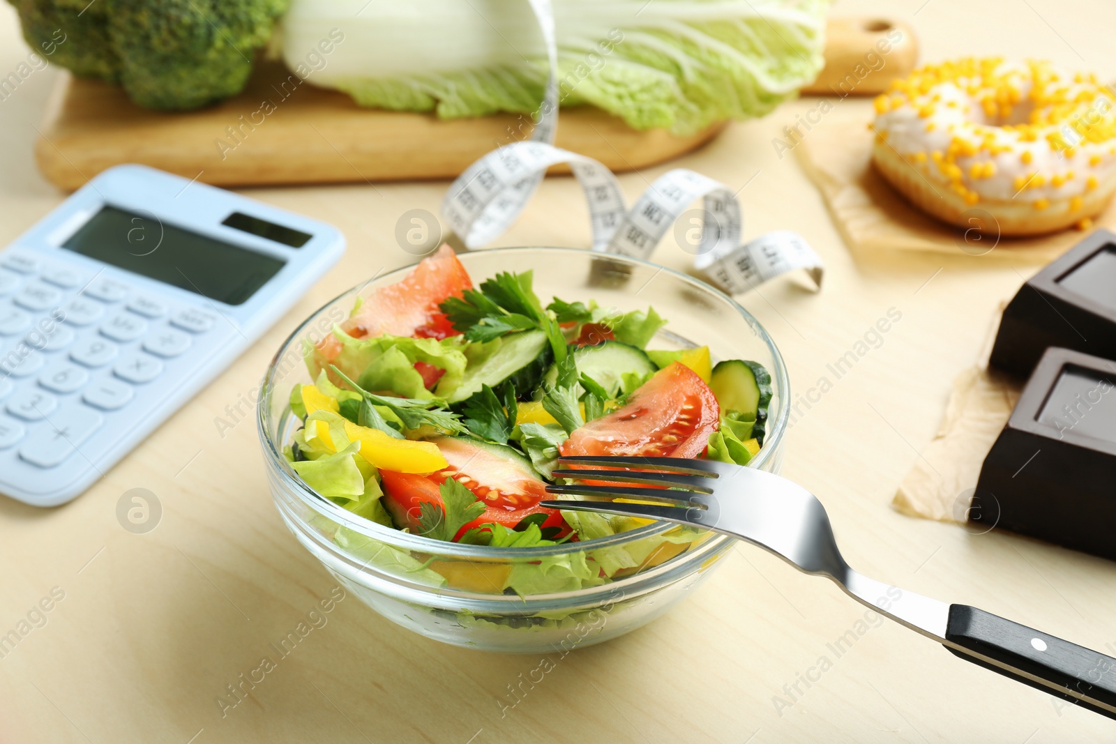 Photo of Calculator, tasty salad in bowl and other food on wooden table. Weight loss concept