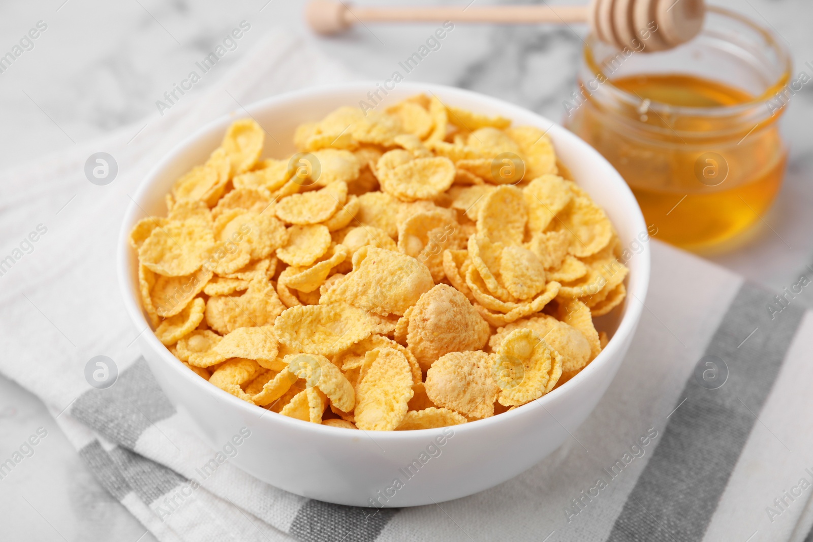 Photo of Tasty crispy corn flakes in bowl on table, closeup. Breakfast cereal