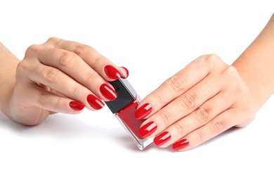 Woman with bright manicure holding bottle of nail polish on white background, closeup