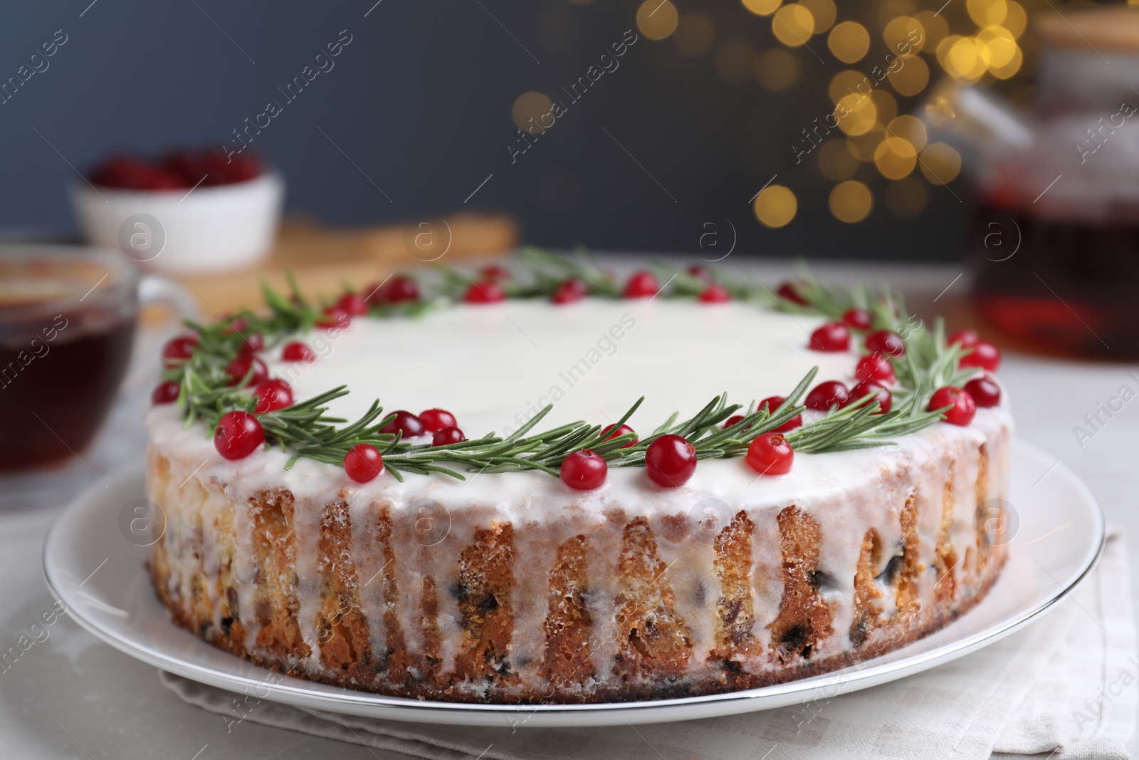 Photo of Traditional Christmas cake decorated with rosemary and cranberries on table, closeup