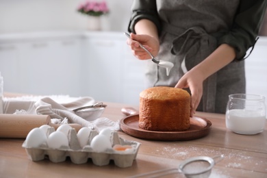 Photo of Young woman with traditional Easter cake in kitchen, closeup. Space for text