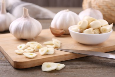 Photo of Aromatic cut garlic, cloves and bulbs on wooden table, closeup