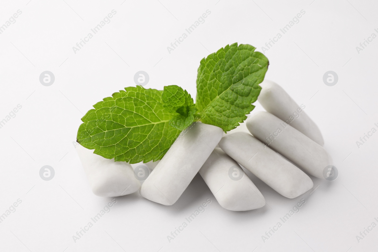 Photo of Tasty chewing gums and mint leaves on white background, closeup