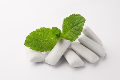 Tasty chewing gums and mint leaves on white background, closeup