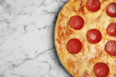 Photo of Tasty pepperoni pizza on white marble table, top view. Space for text