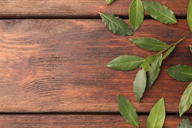 Aromatic fresh bay leaves on wooden table, flat lay. Space for text